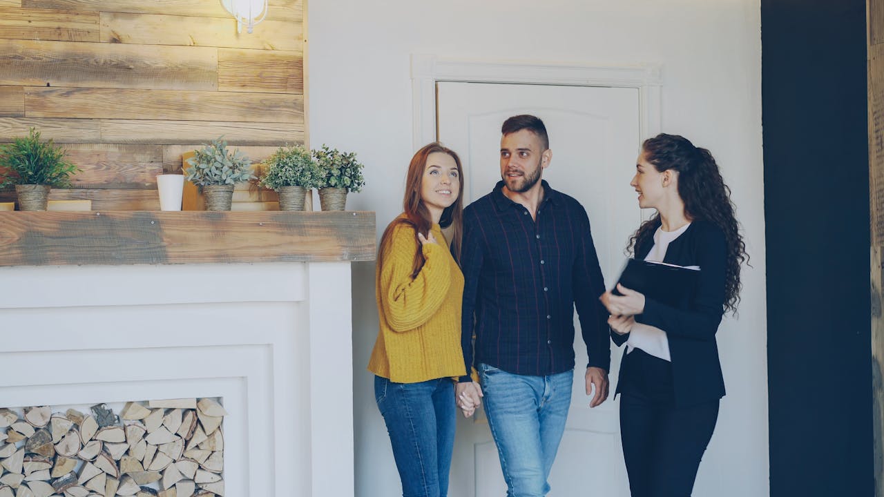 Young couple meeting with real estate agent inside cozy home, exploring purchase options.