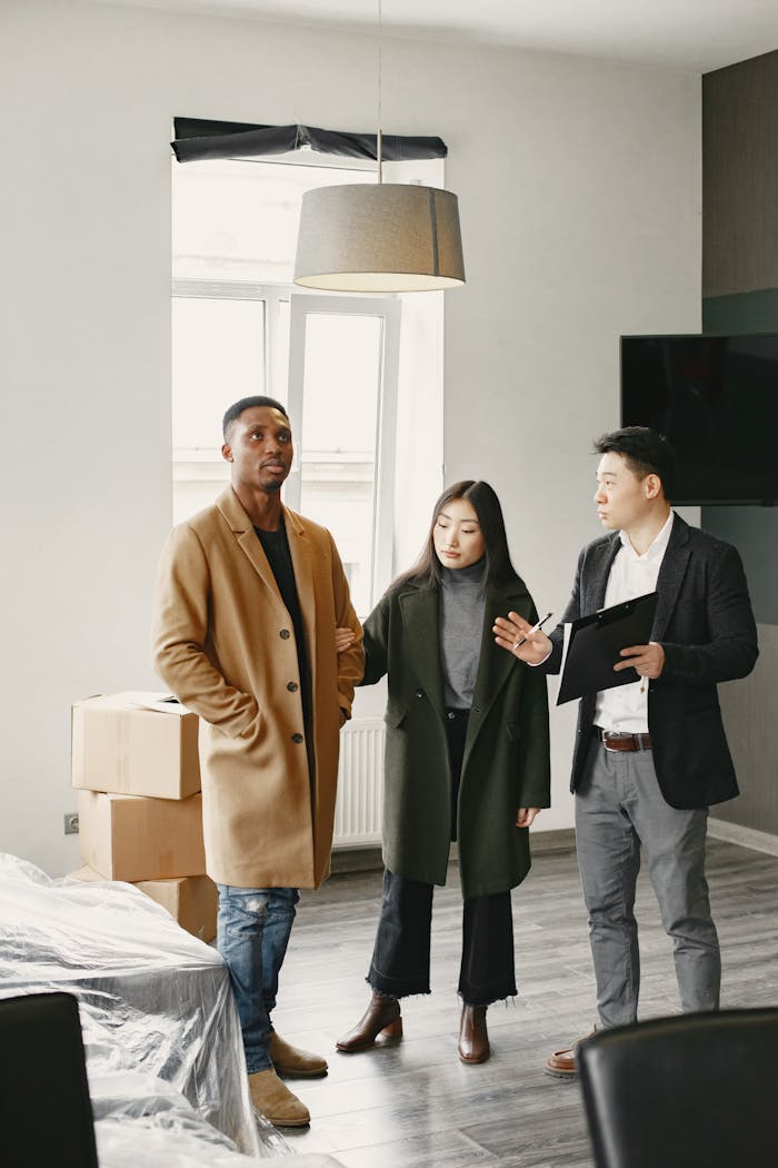 A real estate agent shows a new apartment to a couple indoors. Diverse group discussing property options.