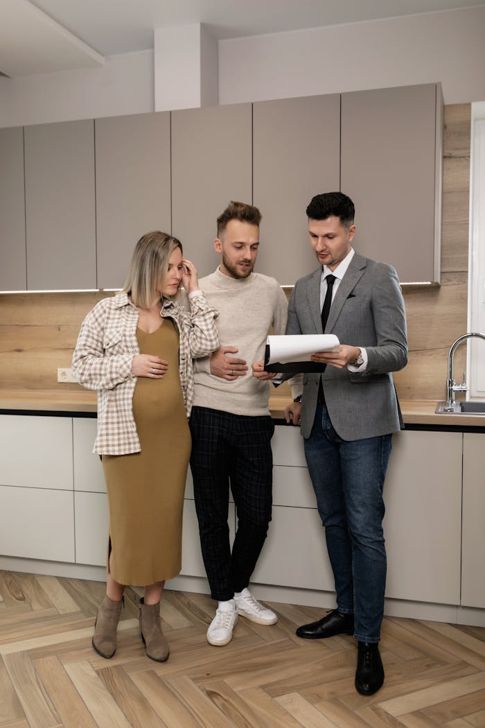 Young couple discusses real estate options with realtor in modern kitchen setting.