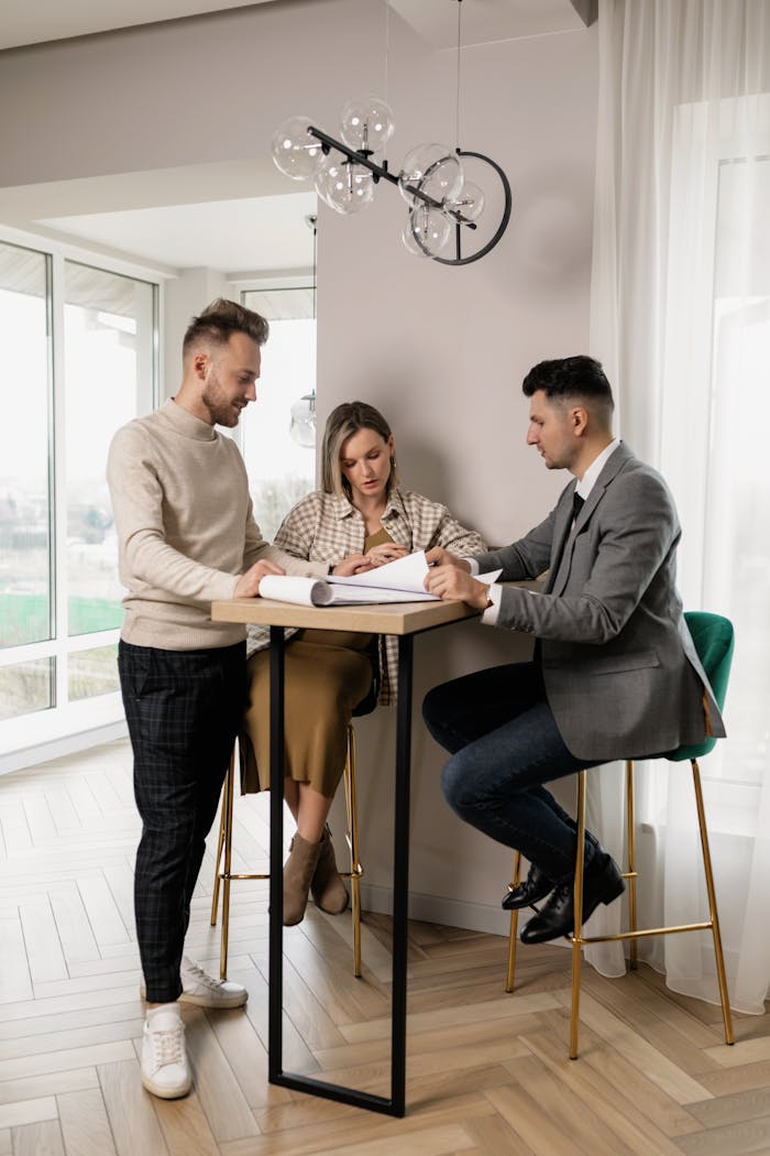 Pregnant couple reviewing property documents with a real estate agent in a bright modern interior.